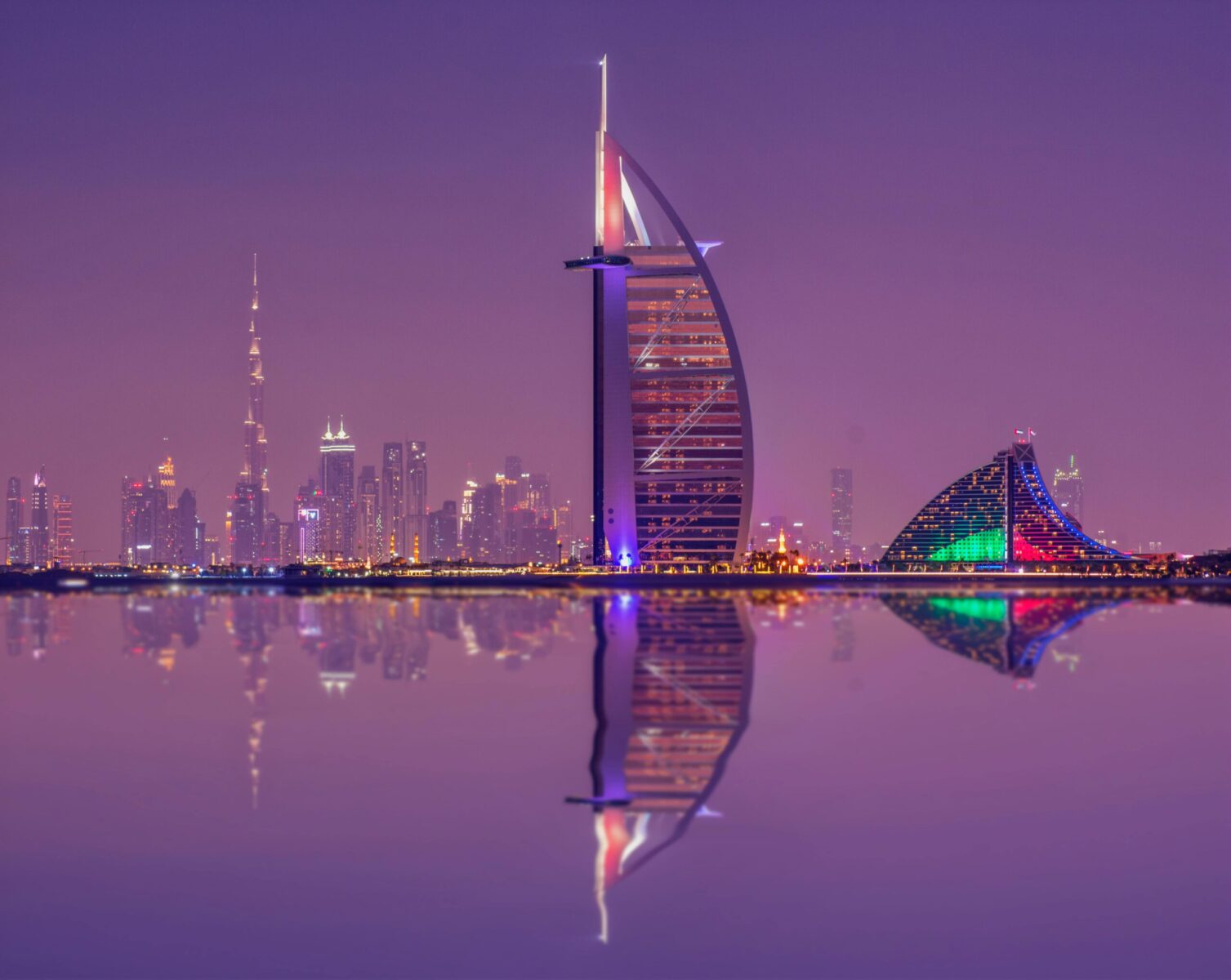 Captivating night scene showcasing Burj Al Arab and Dubai skyline reflections.