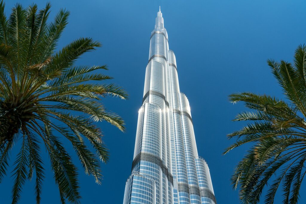 Burj Khalifa building near palm tree under blue sky during daytime